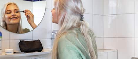 Une salle de bain avec des carreaux blancs, un miroir rond et un lavabo.