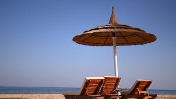 Privat strand, parasoller, strandhåndklær og sandvolleyball