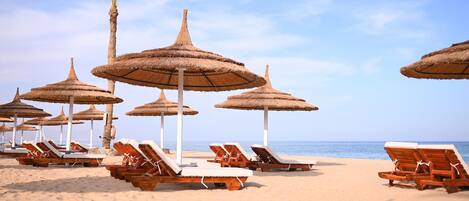 Privat strand, parasoller, strandhåndklær og sandvolleyball