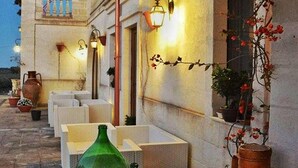 An outdoor seating area with wicker furniture, terracotta pots, and a stone archway. - Agriturismo I Pozzetti (Fasano)