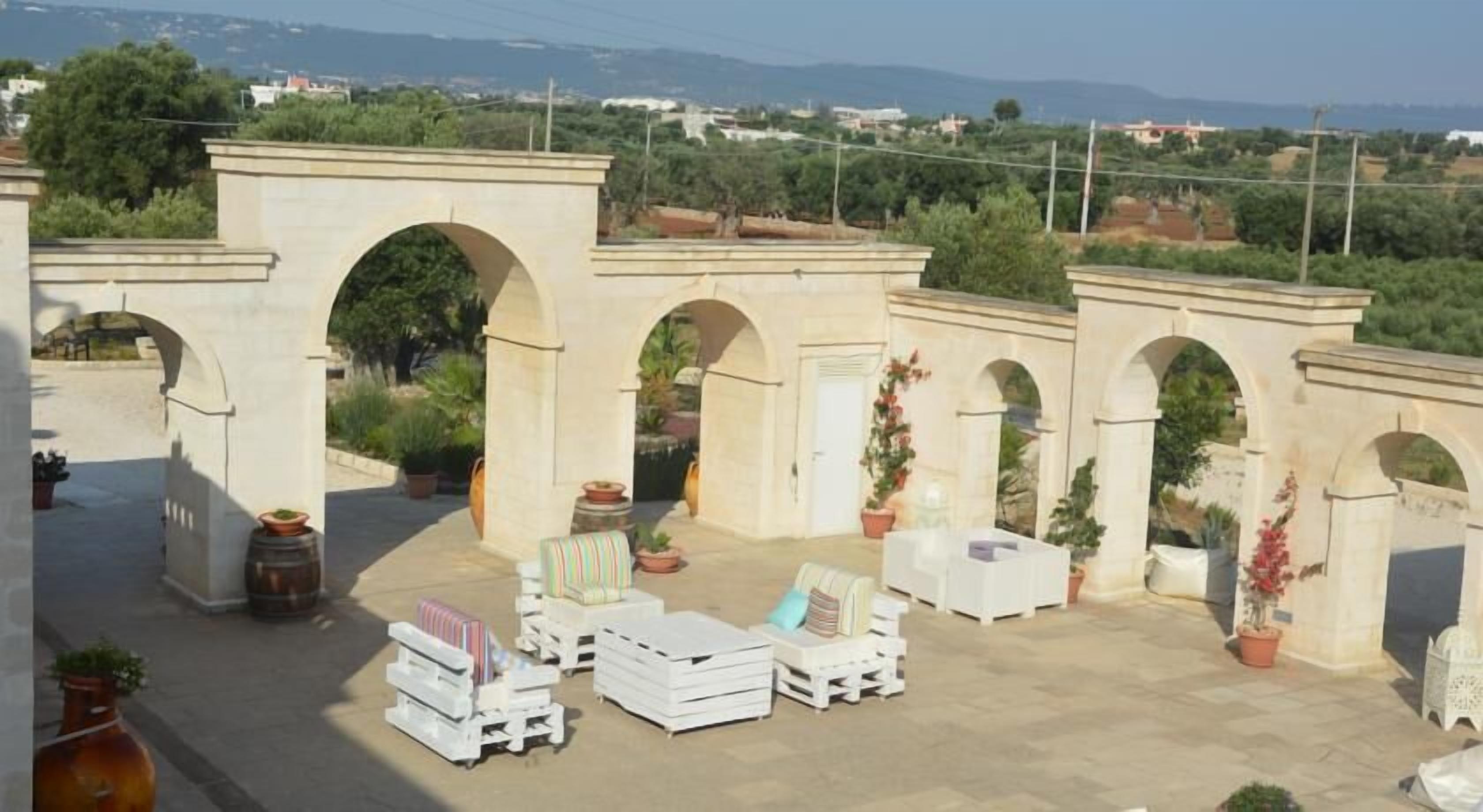 Eine Dachterrasse mit Sitzgelegenheiten im Freien, Pflanzgefäßen und Blick auf die umliegende Landschaft.