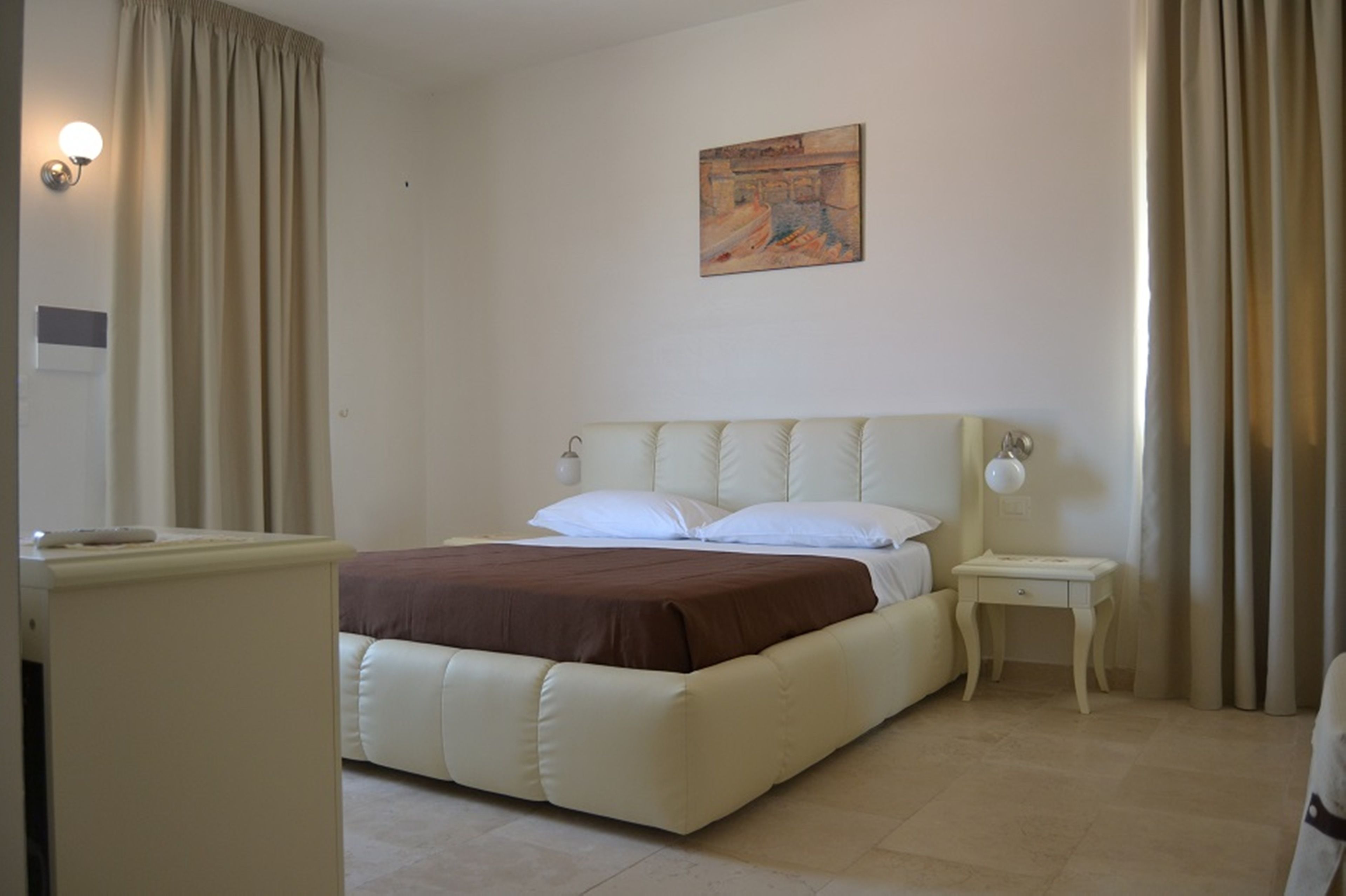 Un dormitorio con una cama grande, una mesita de noche, una lámpara y un cuadro en la pared.