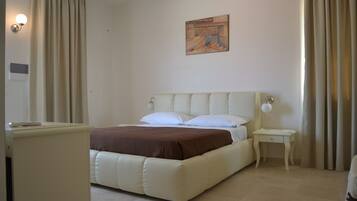 Un dormitorio con una cama grande, una mesita de noche, una lámpara y un cuadro en la pared.