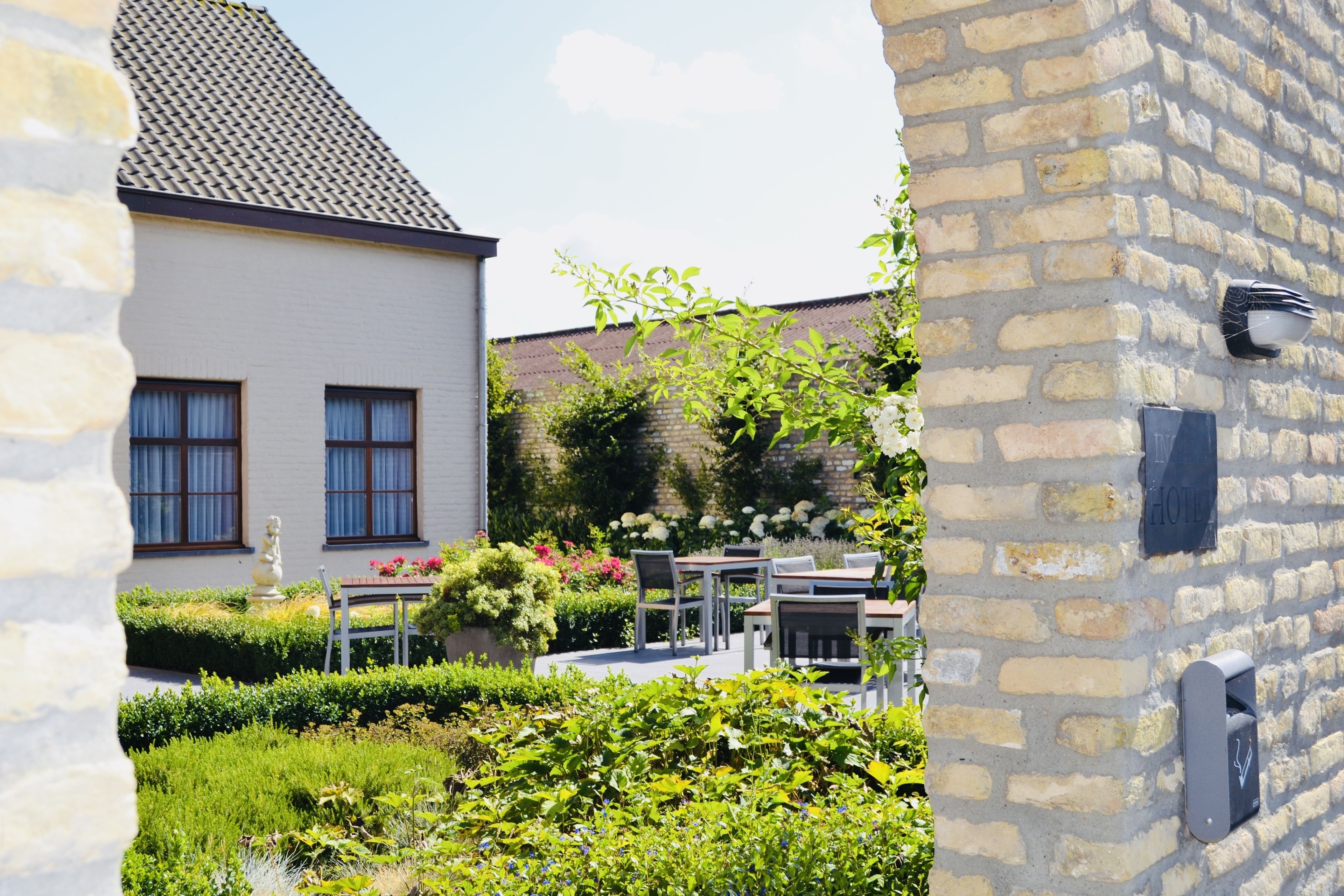A courtyard with a white building, outdoor seating, and a stone wall.