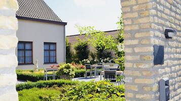 A courtyard with a white building, outdoor seating, and a stone wall.