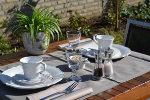 Una mesa dispuesta para una comida con platos, vasos, cubiertos y una planta en maceta.