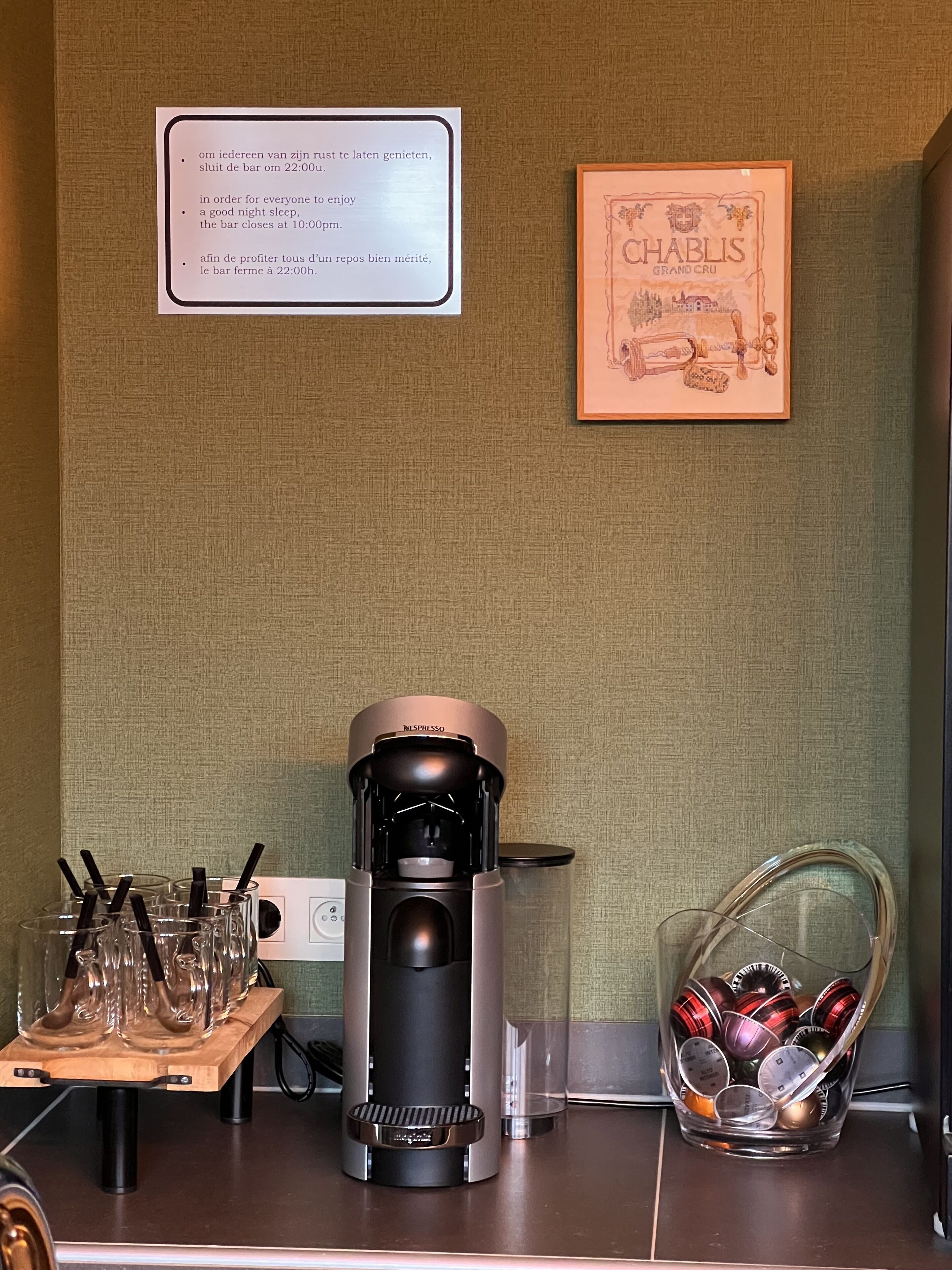 Una cafetera, un vaso de agua y un cartel en la pared.