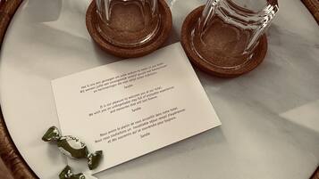 A welcome card on a marble table with two clear glasses on coasters.