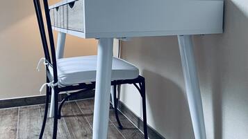 Ein weißer Schreibtisch mit einer Lampe, einem Stuhl und einer kleinen Schachtel darauf.