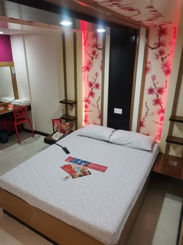 A hotel room with a bed, a desk, a chair, and a phone.