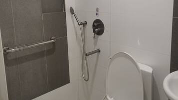 Een moderne badkamer met douche, toilet en handgreep.