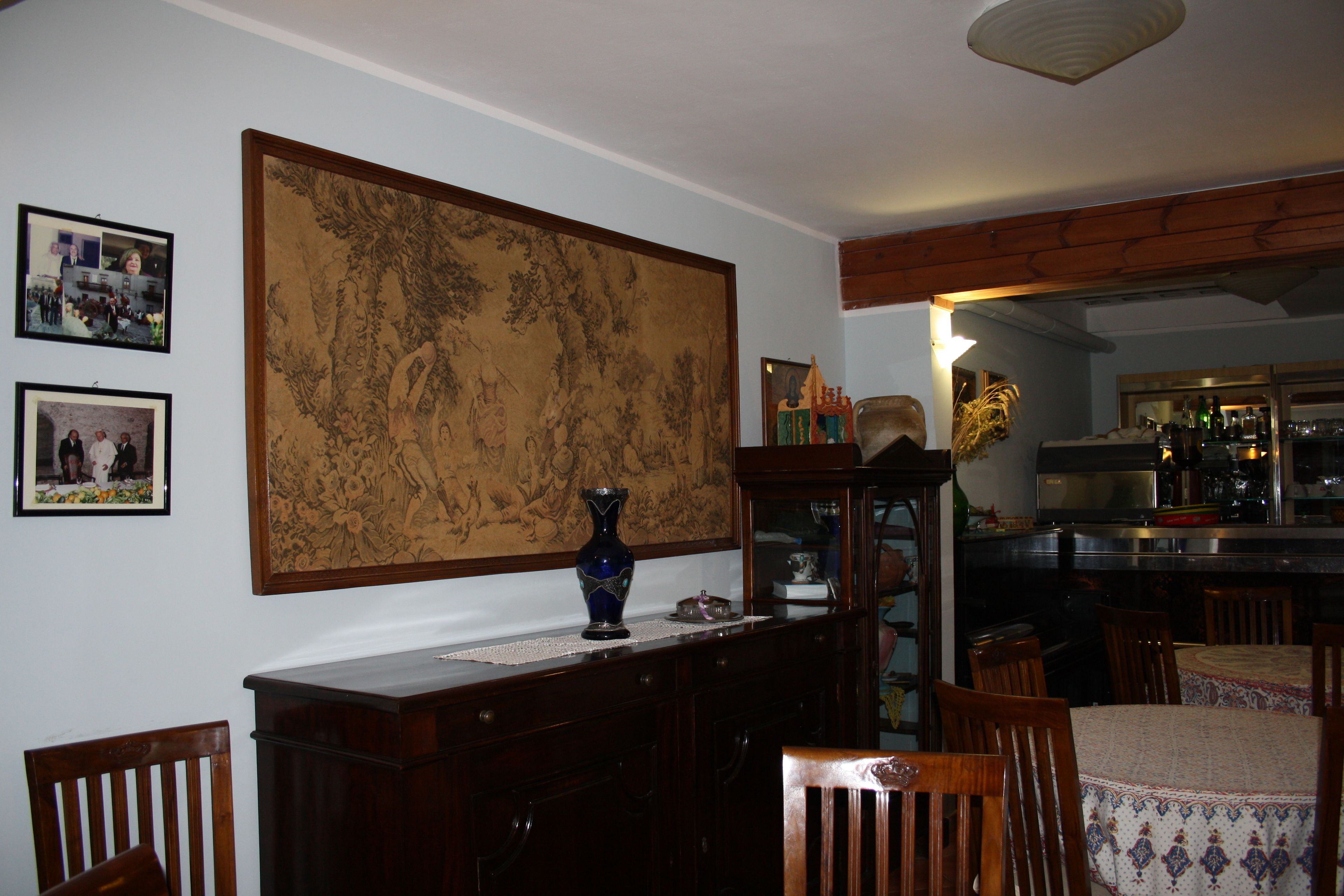 Un espace repas avec des meubles en bois, un grand panneau décoratif et une cuisine en arrière-plan.