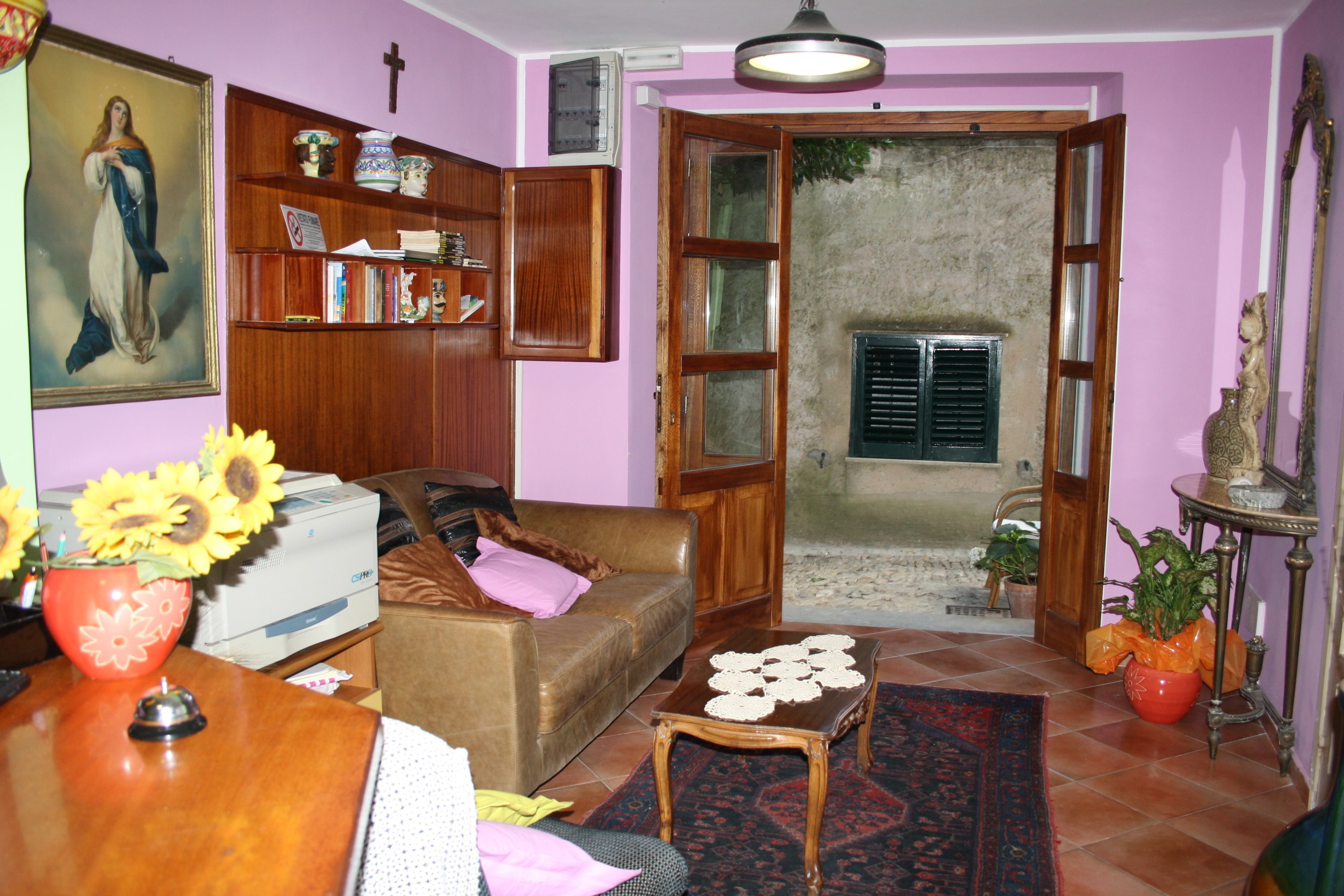 A living room with a sofa, a coffee table, a bookshelf, and a painting on the wall.