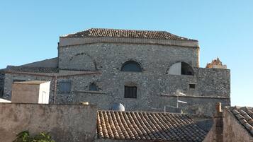 A historic stone building with a tiled roof, arched windows, and a small bell tower.