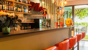 A bar area with stools, shelves of bottles, and hanging light fixtures.