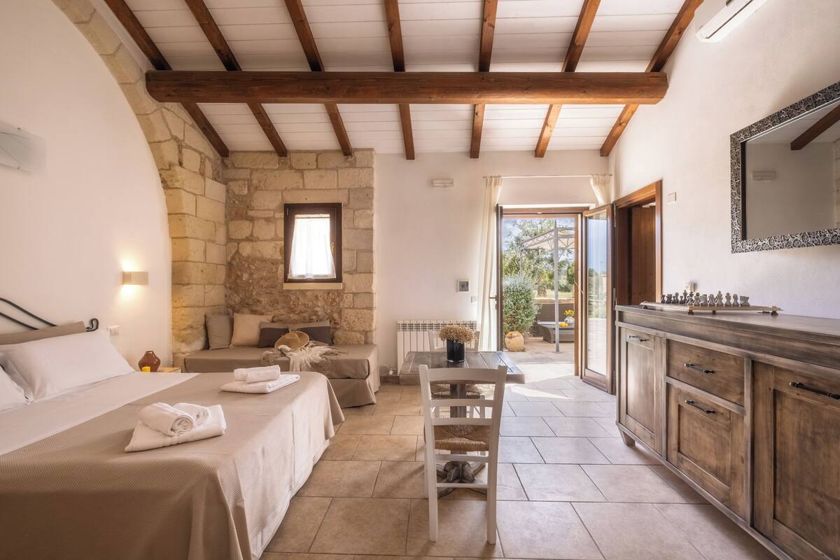 Un dormitorio acogedor con pared de piedra, techo de madera y un ventanal grande.