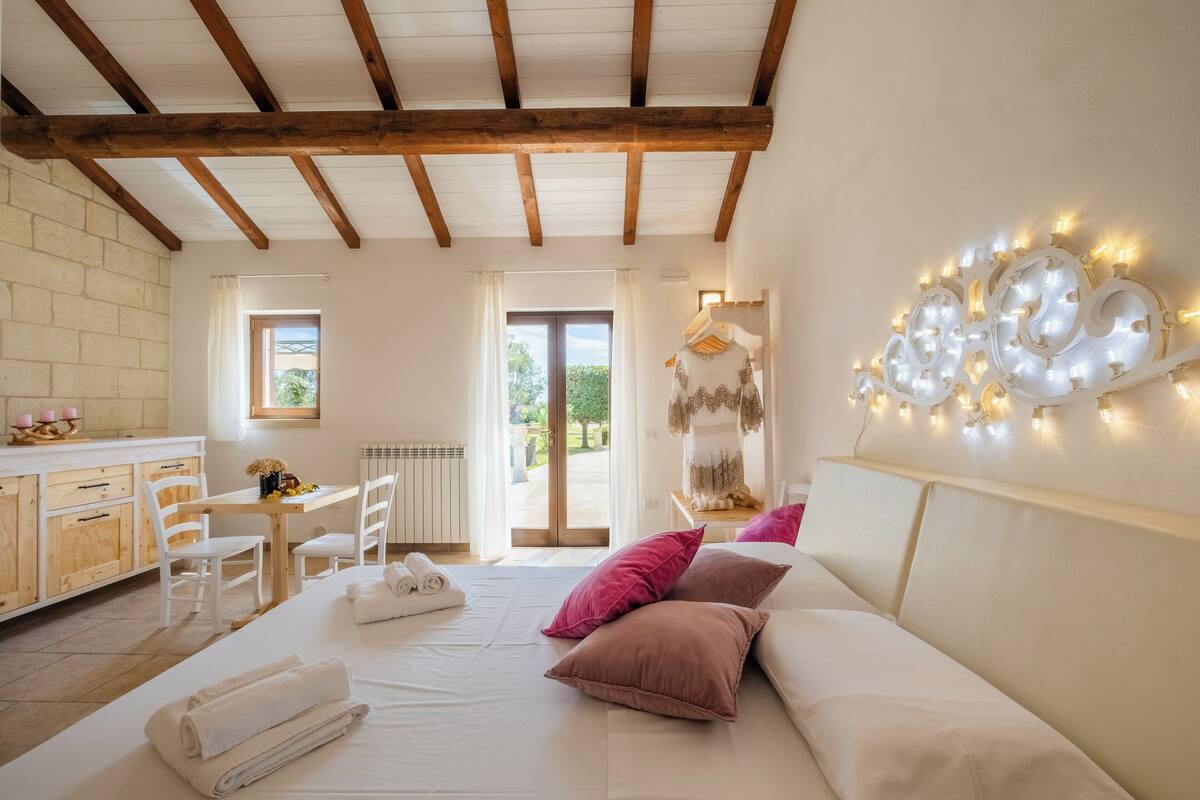 Un dormitorio con cama, almohadas, cómoda y ventana.