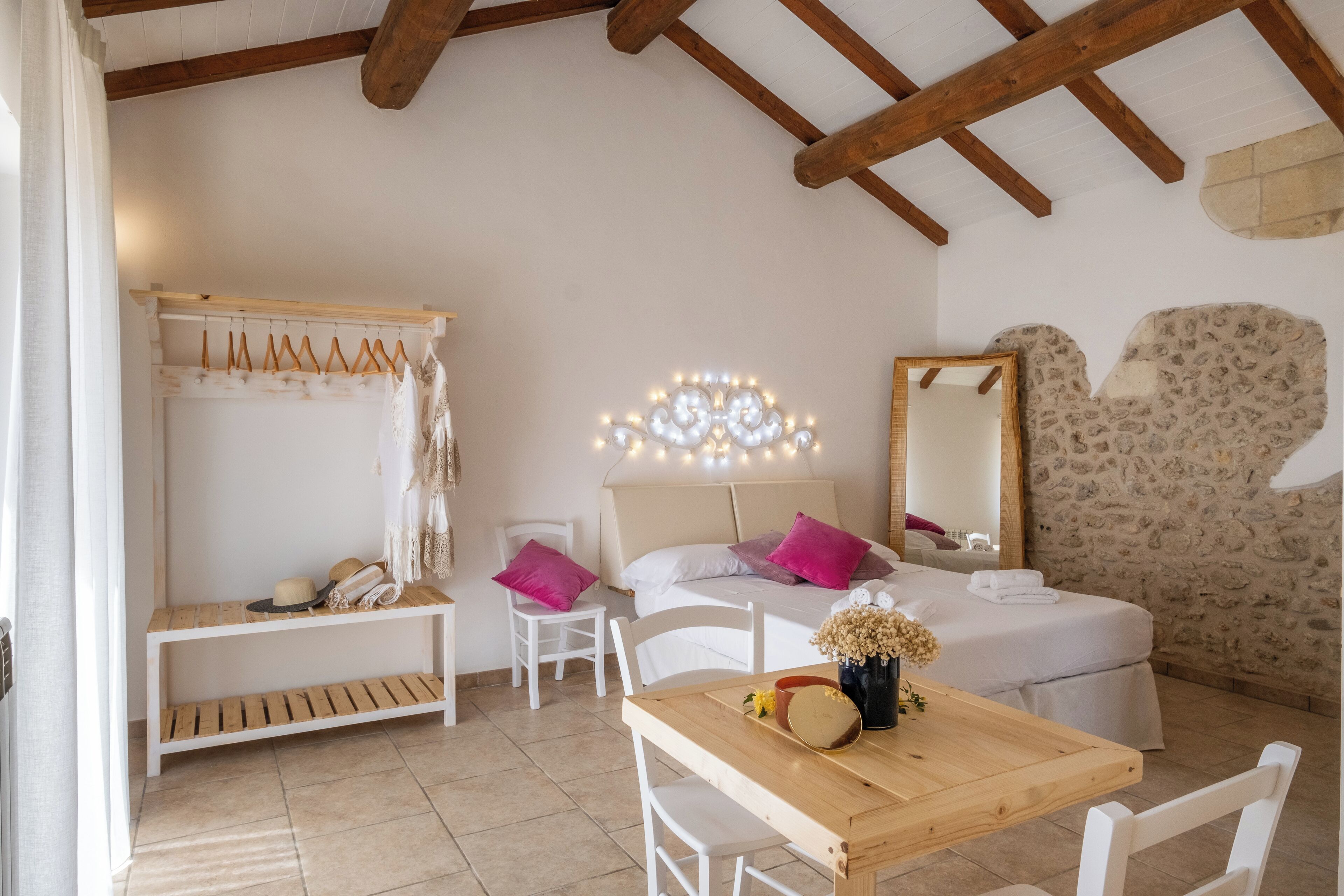 Ein Schlafzimmer mit Bett, Nachttisch, Kleiderständer und Spiegel.
