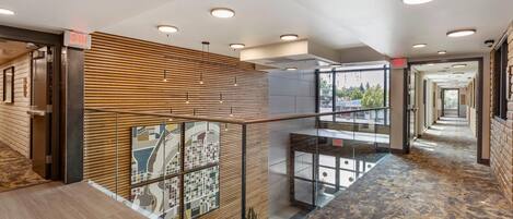 A modern hotel lobby with a wooden slatted wall, glass railings, and a patterned carpet.