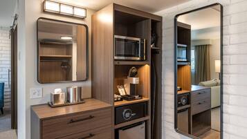 A compact kitchenette with a microwave, refrigerator, and a small cabinet with a mirror.