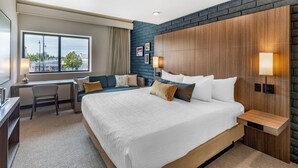 A modern hotel room with a large bed, a desk, and a view of the city. - The Gibson Hotel Great Falls, an Ascend Collection Hotel (Great Falls)