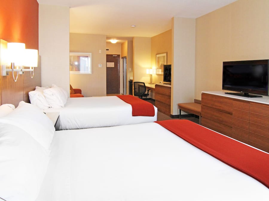 Habitación de hotel con dos camas, televisión, escritorio y una silla.