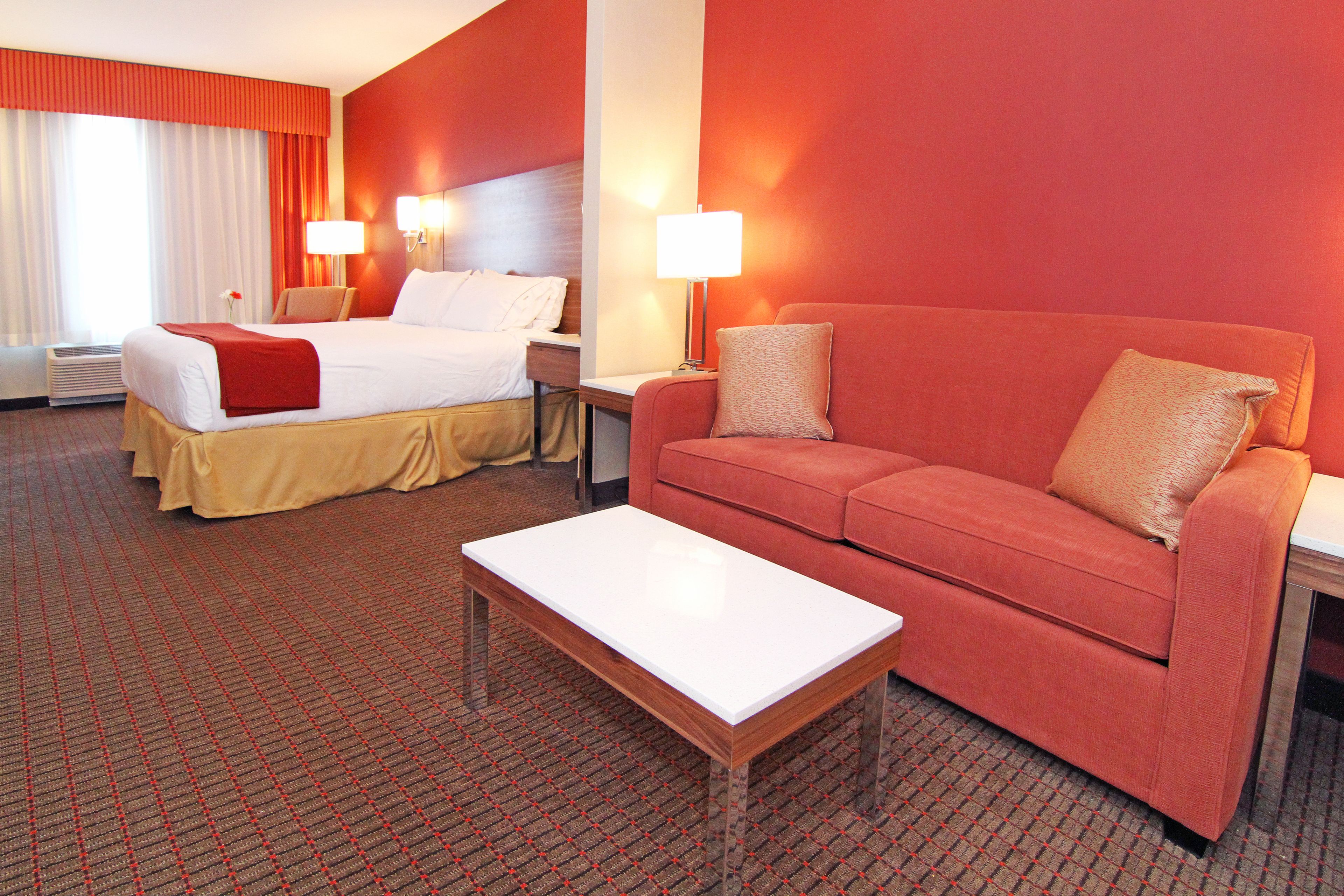 A hotel room with a bed, a sofa, a coffee table, and two bedside lamps.