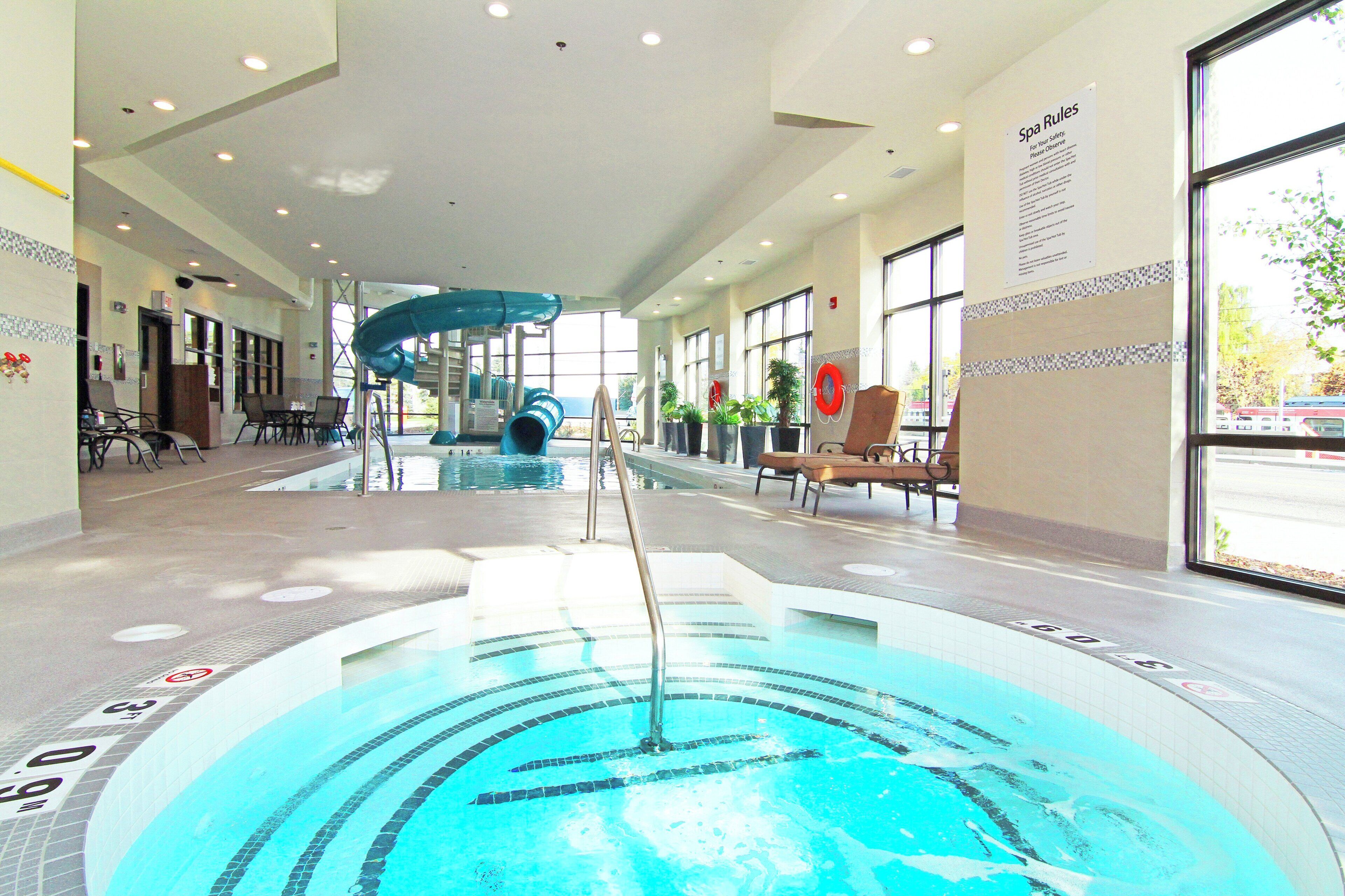 A swimming pool with a slide, lounge chairs, and a sign indicating spa rules.