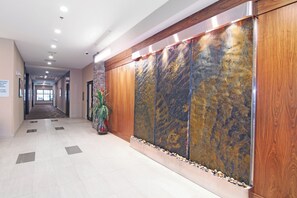 A hotel corridor with a marble wall, a potted plant, and a tiled floor. - Holiday Inn Express & Suites Calgary NW - University Area by IHG (Calgary)