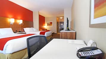 A hotel room with two beds, a desk, a telephone, and a television.