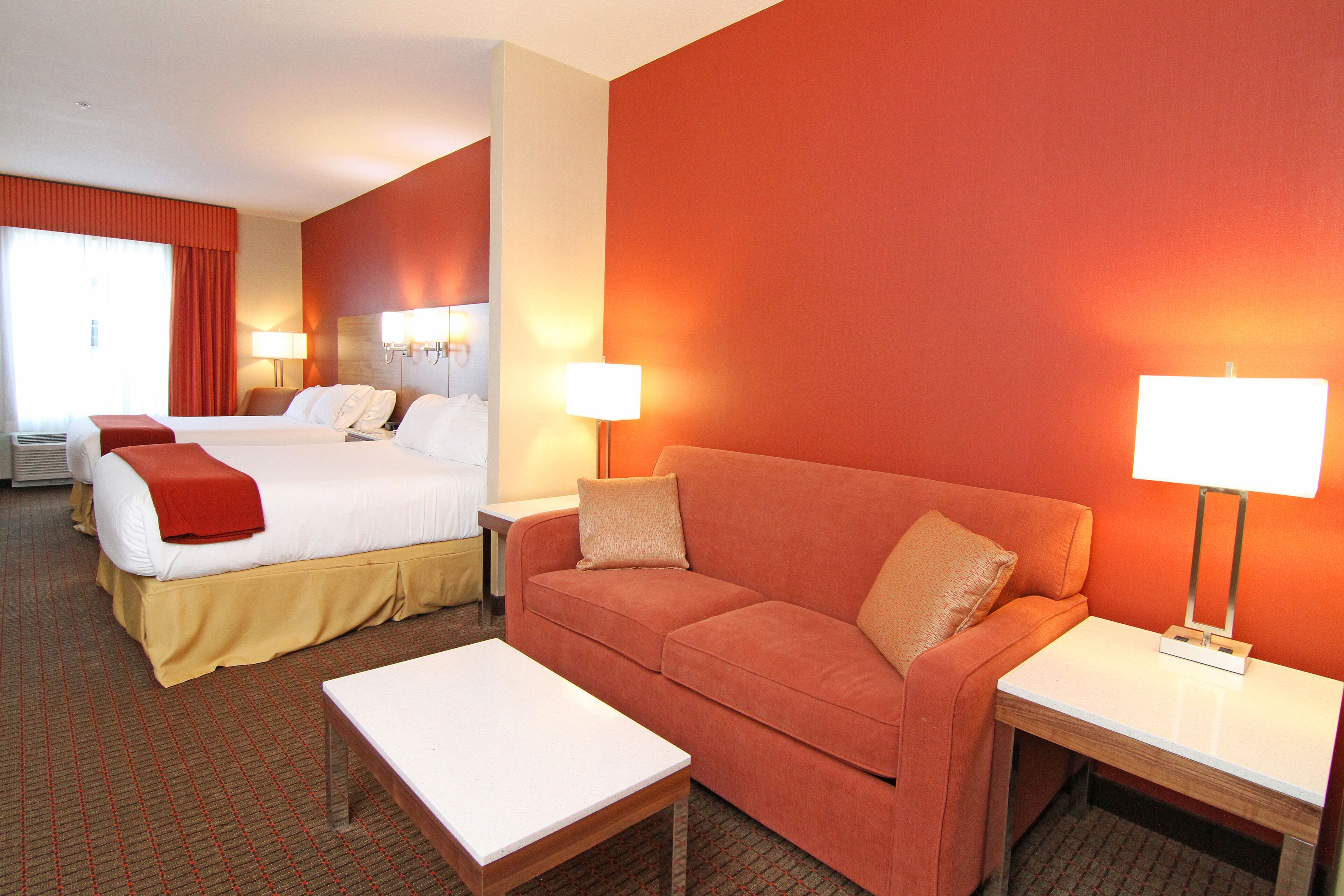 A hotel room with a bed, a sofa, a coffee table, and two lamps.