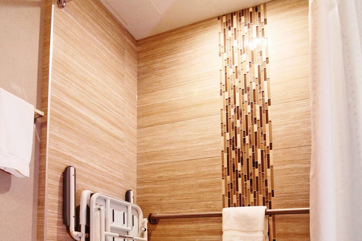 A shower area with a grab bar, a towel rack, and a shower curtain.