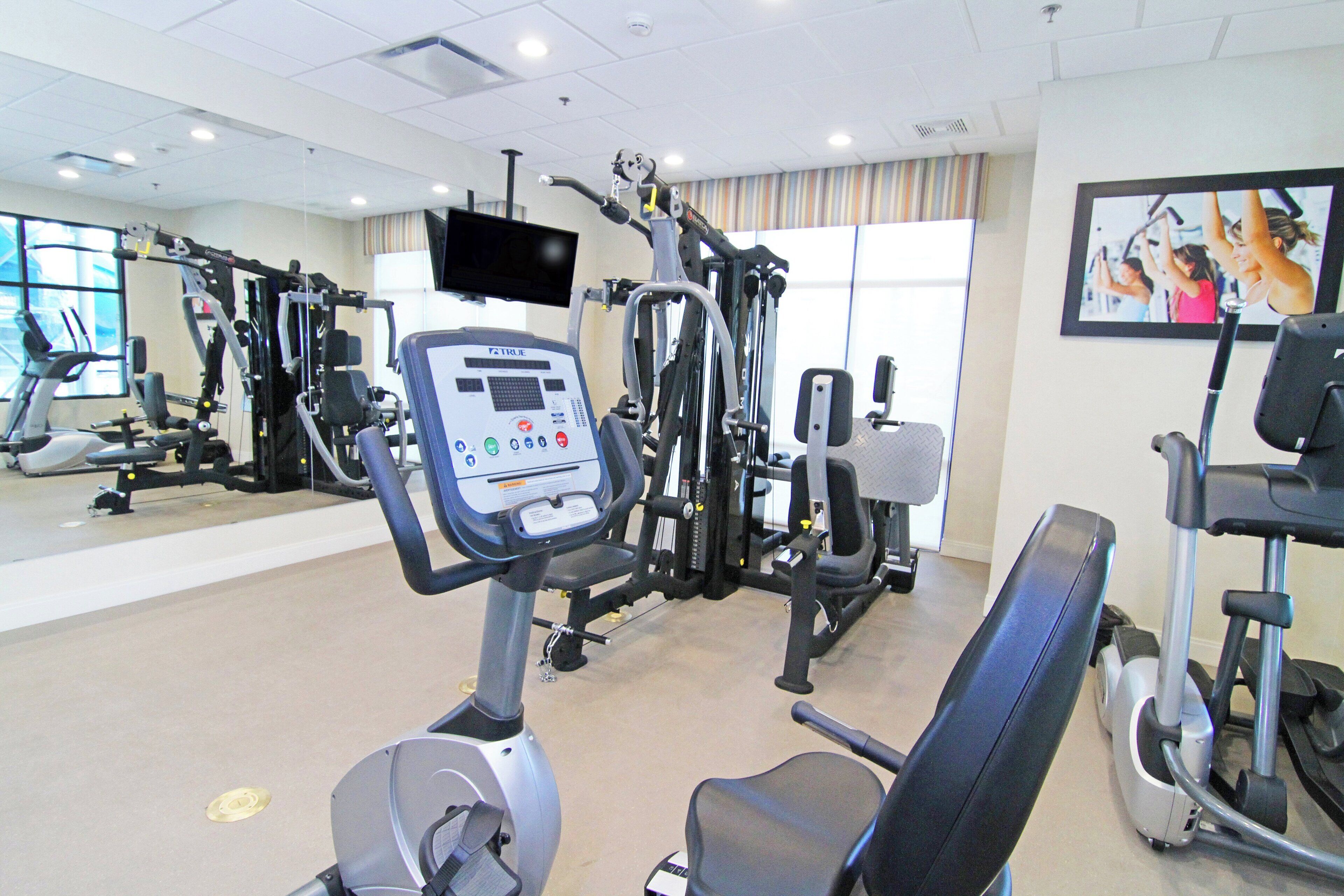 A gym with various exercise equipment, a television, and a mirror.