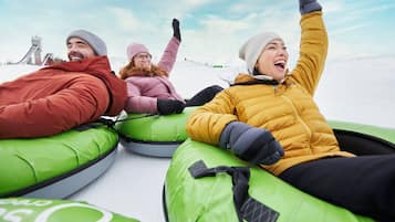 Quatro pessoas escorregando em boias infláveis verdes.