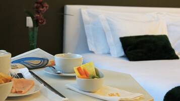 A neatly arranged breakfast table with a bowl of fruit, a cup, and a plate of food.
