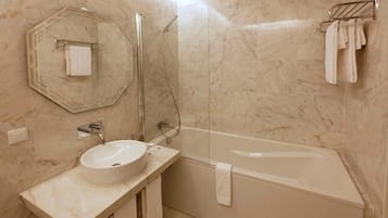Un baño con pared de mármol, un lavamanos redondo, ducha con cerramiento de vidrio y un perchero para toallas.