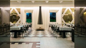 A restaurant with a checkered floor, tables set for dining, and a central decorative pillar. - HD Duecitânia Design Hotel (Penela)