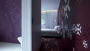 Moderni hotellihuone, jossa on sänky, kylpyhuone ja näkymä ulos.