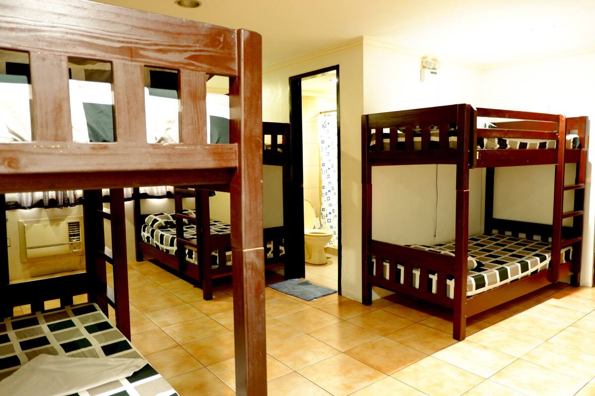 A room with bunk beds, a wooden chair, and a tiled floor.