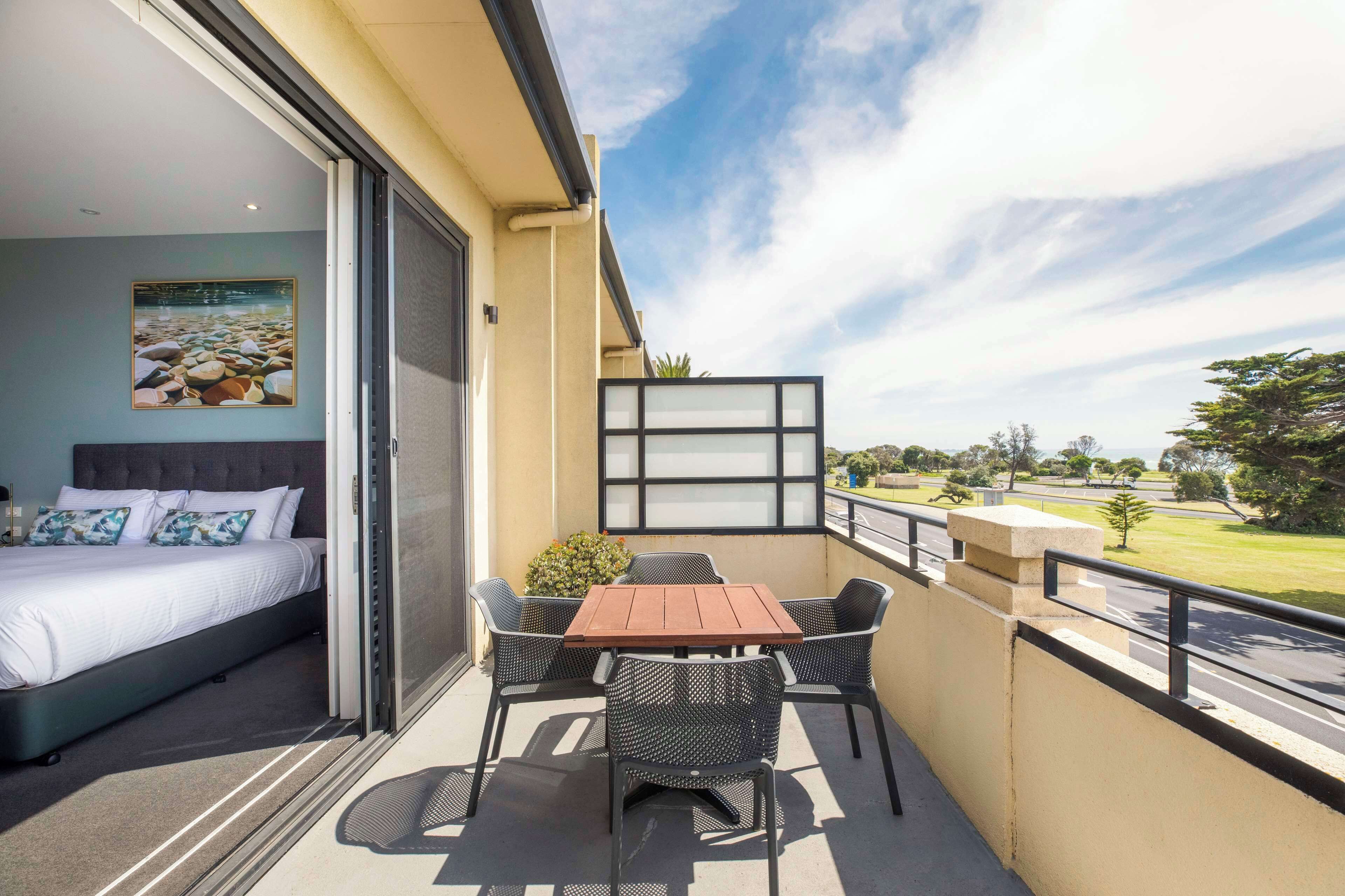 A balcony with a bed, a table, and chairs.