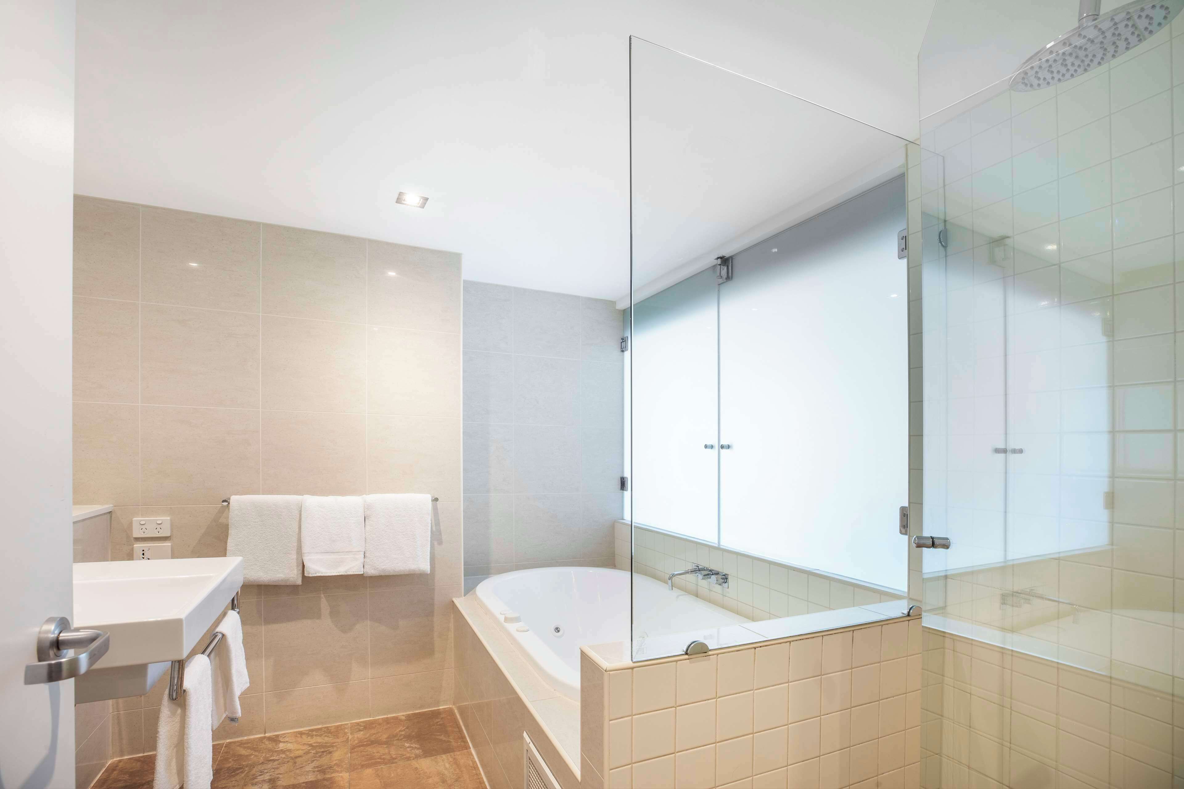 A modern bathroom with a glass-enclosed shower, a bathtub, and a vanity with a mirror.
