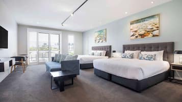 Une chambre d’hôtel moderne avec deux lits, un bureau, une chaise et une grande fenêtre.