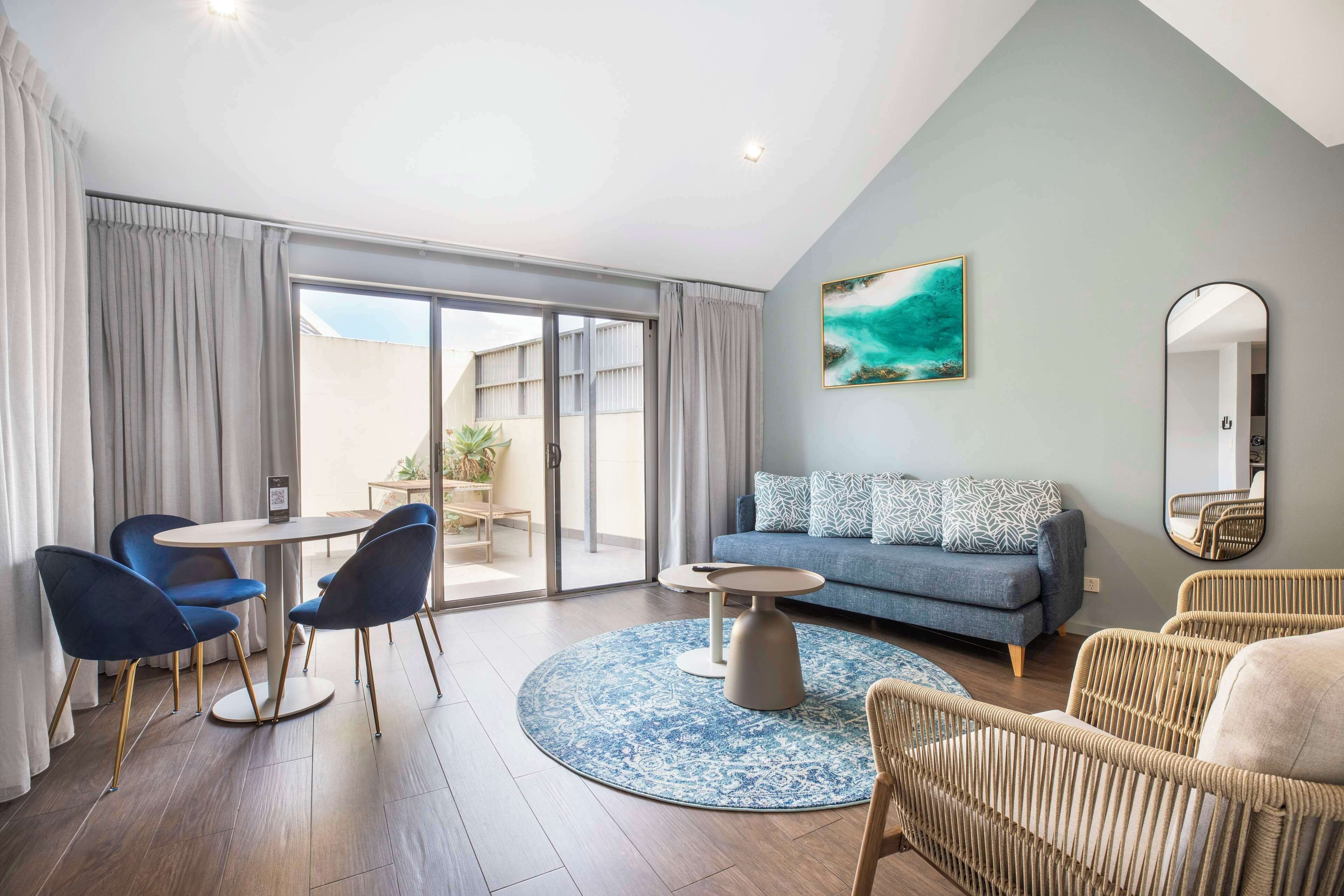 A modern living room with a sofa, two armchairs, a coffee table, and a round rug.