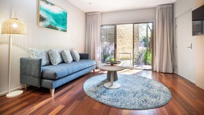 A modern living room with a blue sofa, a round coffee table, and a patterned rug.