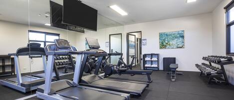 A gym with treadmills, exercise bikes, and dumbbells.