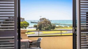 A balcony with a view of the sea, a pier, and a roundabout.