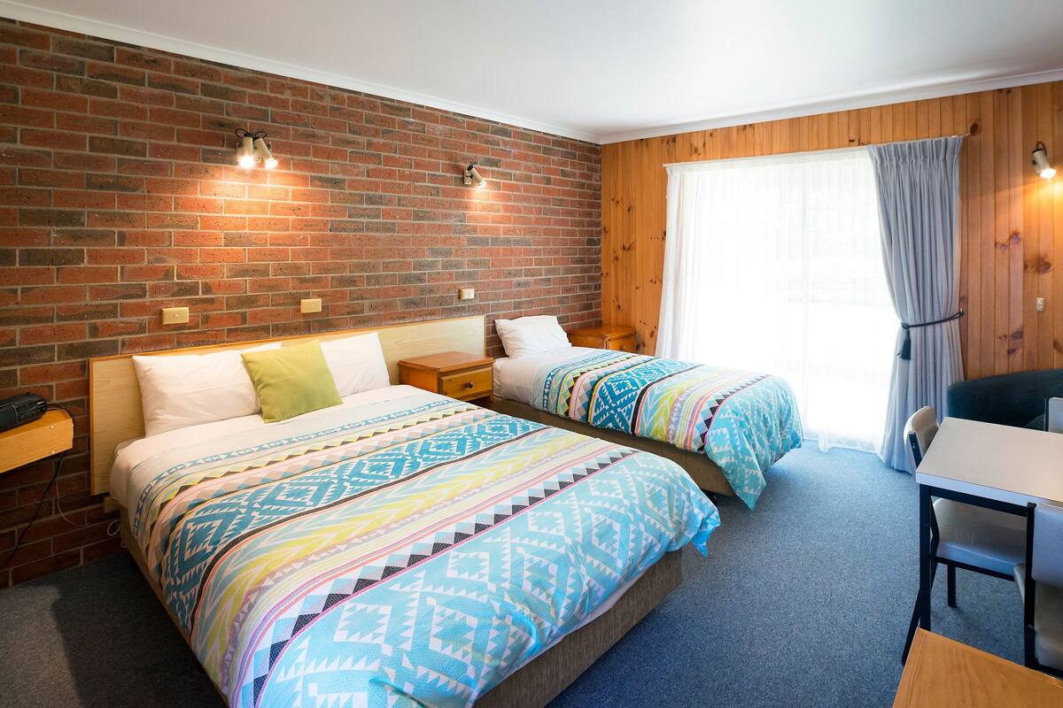 Ein Hotelzimmer mit zwei Betten, einem Schreibtisch und einem Stuhl.