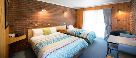 A hotel room with two beds, a desk, and a chair.