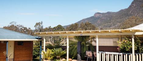 A motor lodge with a covered outdoor seating area, a BBQ, and a view of a mountain.