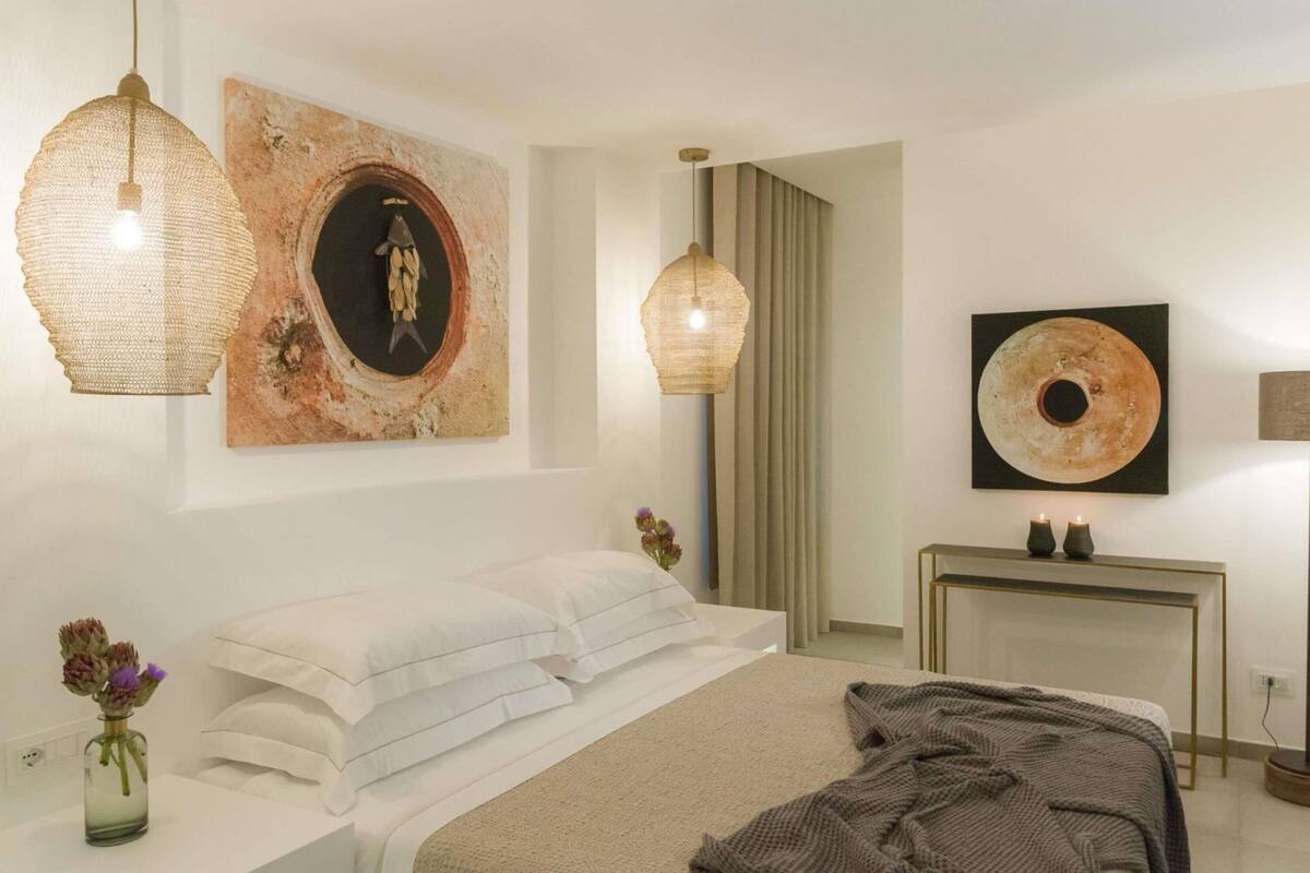 Un dormitorio moderno con cama, mesitas de noche, una consola y obras de arte en las paredes.